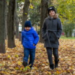 Мальчик и девочка подбрасывать желтые листья ногами в парке осенью - Украина, Одесса, 17,10,2019