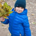 Мальчик позирует в парке с осенними листьями