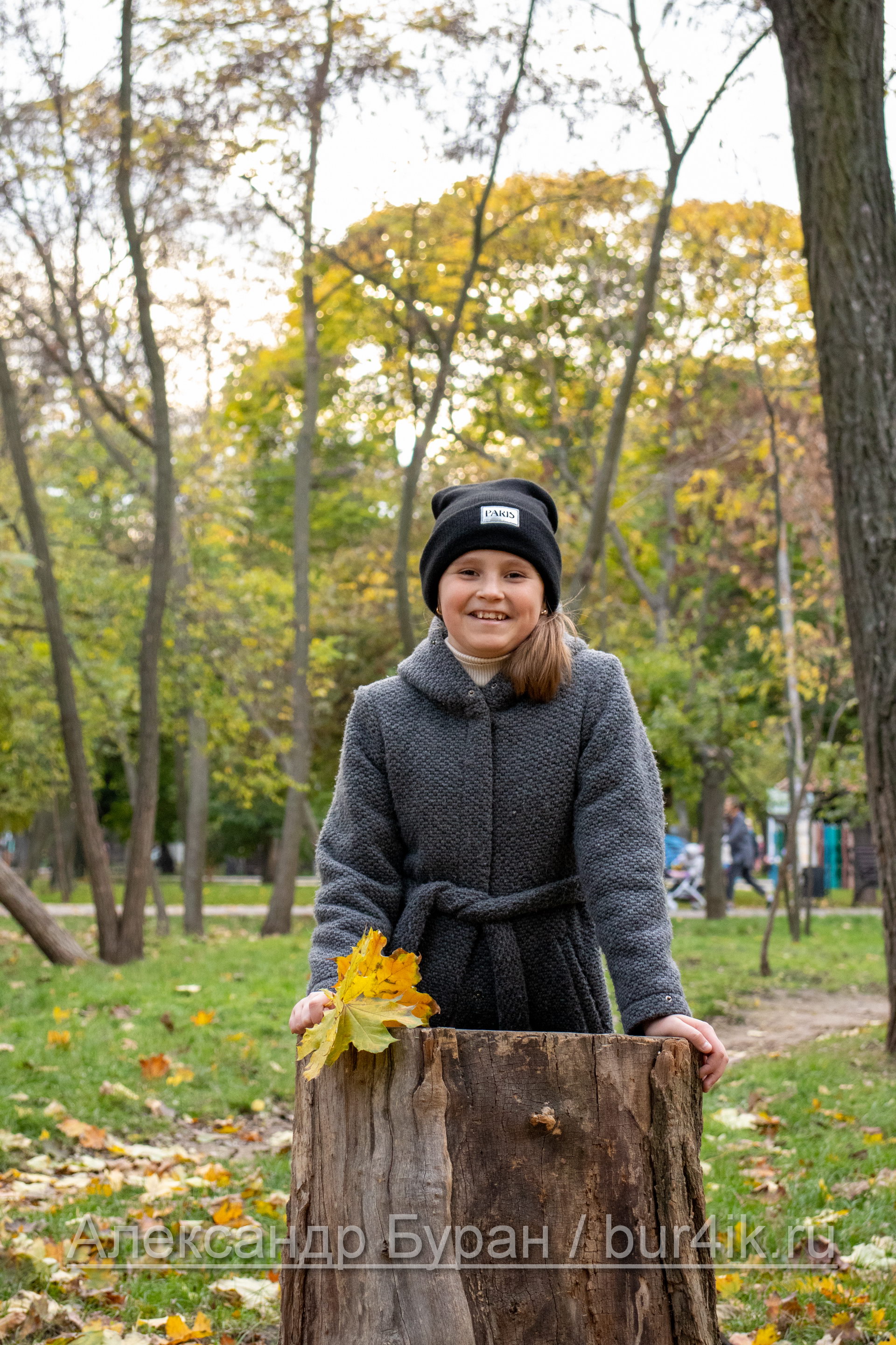 Девушка в сером пальто и черной шляпе в осеннем парке