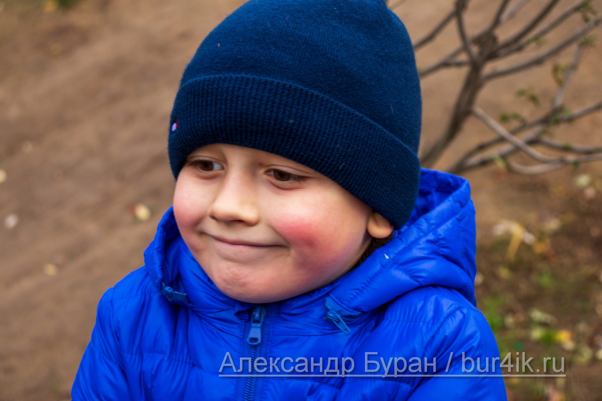 Улыбка мальчик с красными щечками в осеннем парке