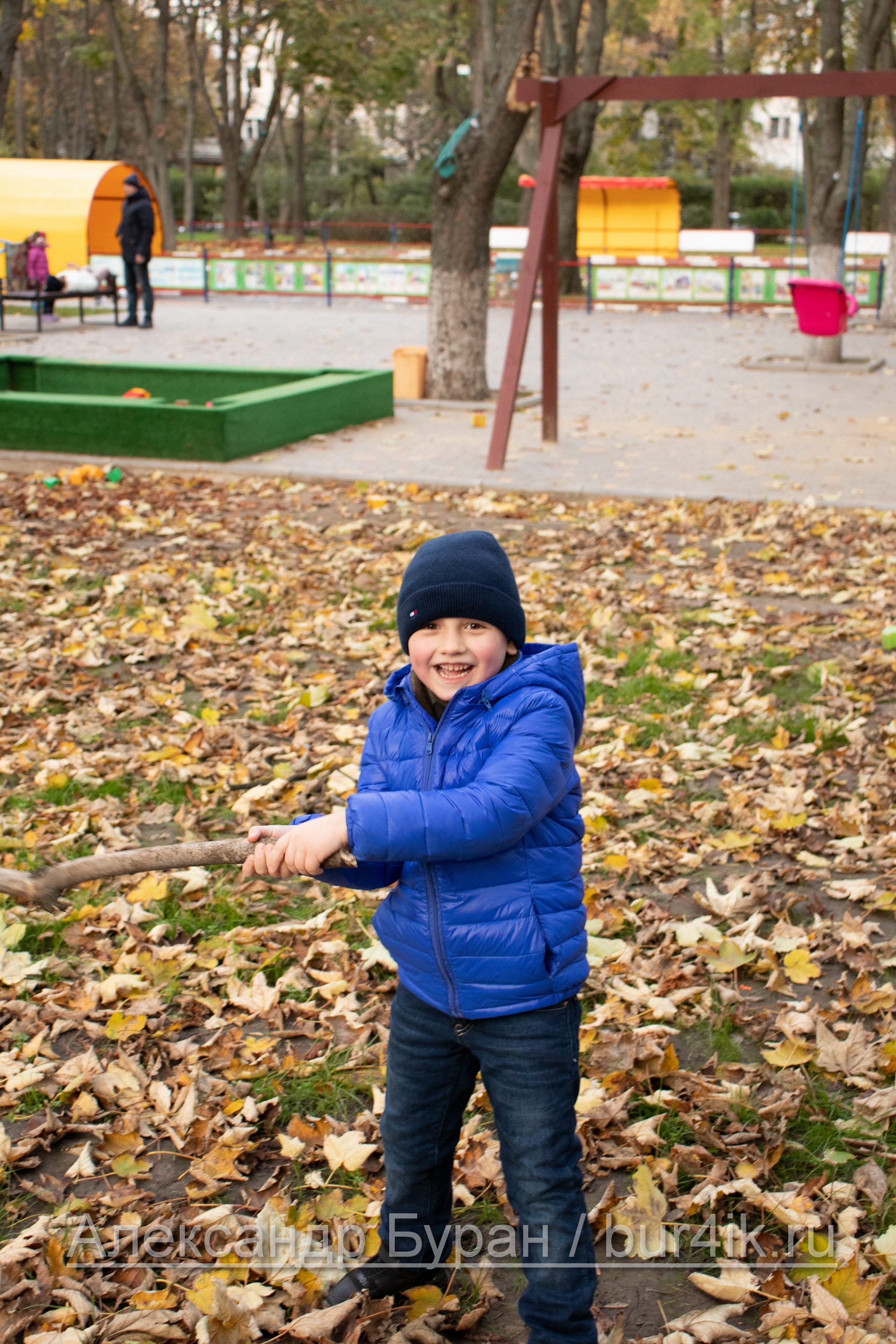 Мальчик с веткой дерева в руках в осеннем парке