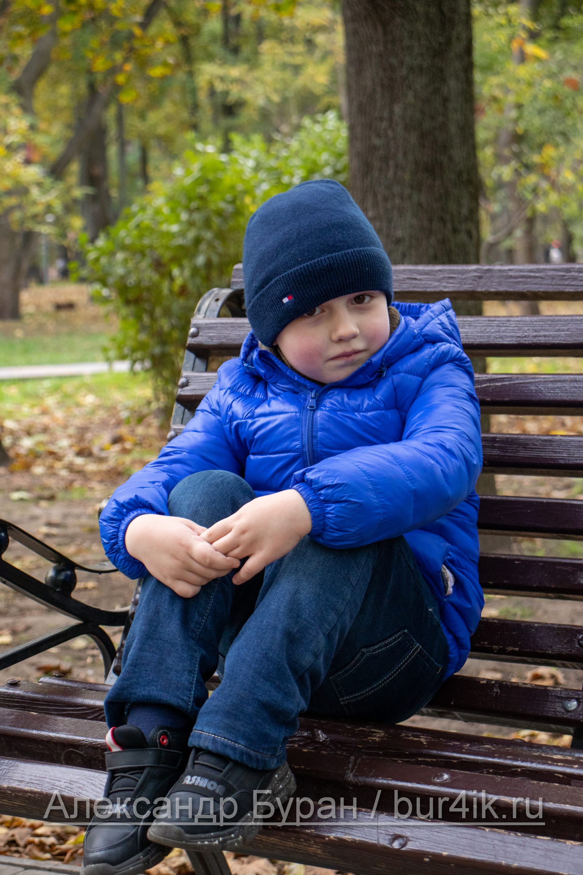 Мальчик в парке залезла на скамейку с ногами