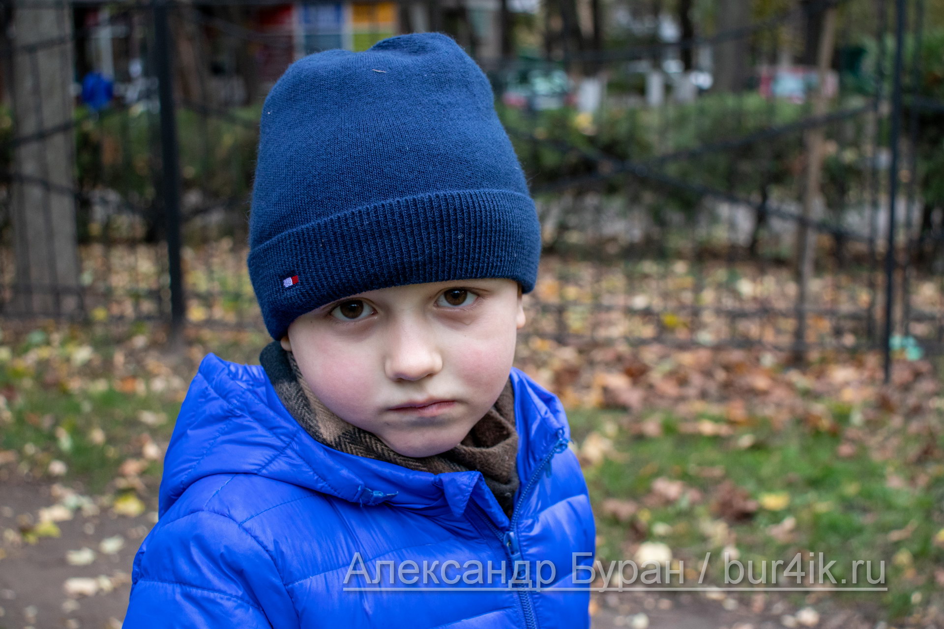 Мальчик в плохом настроении на прогулке в парке осенью