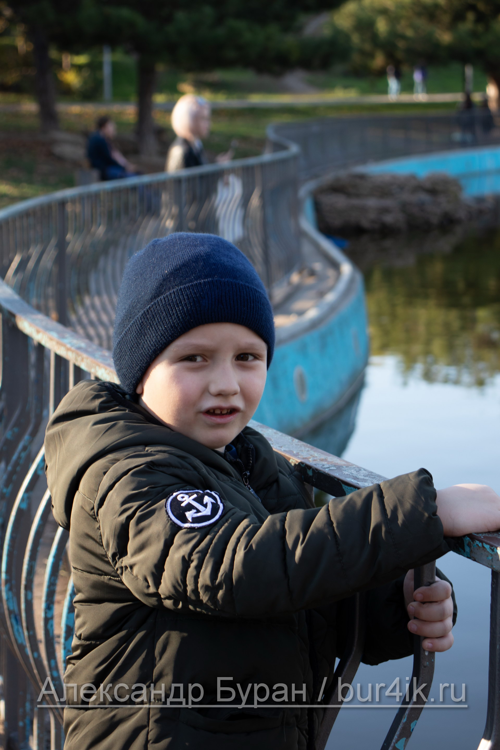 Мальчик на перила вокруг пруда в парке