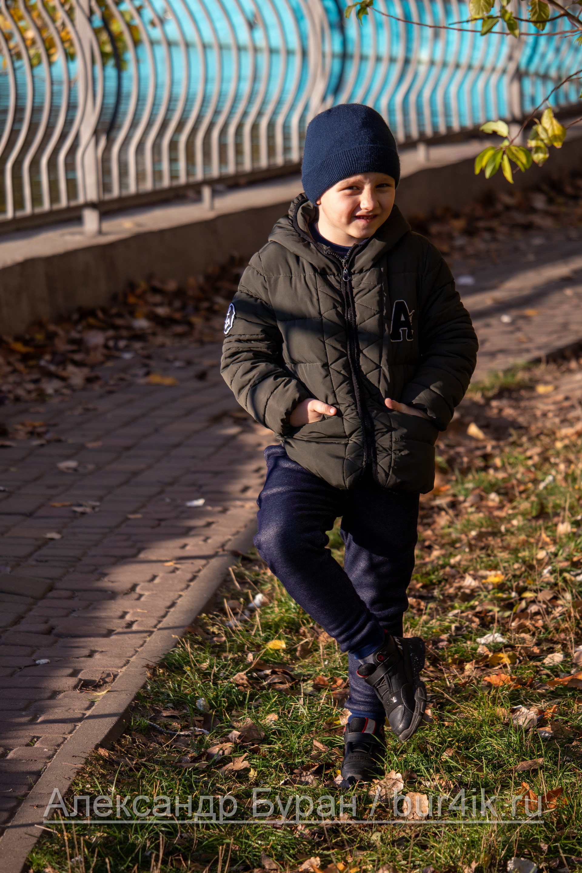 Мальчик фотографируется возле пруда в осеннем парке