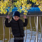 Мальчик спиной к озеру в парке