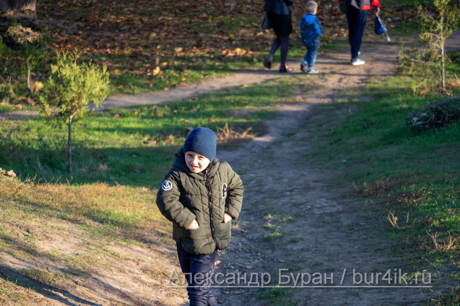 Мальчик в шляпе бежит вниз по холму в парк
