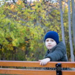 Мальчик сидит на скамейке в перерыве в осеннем парке