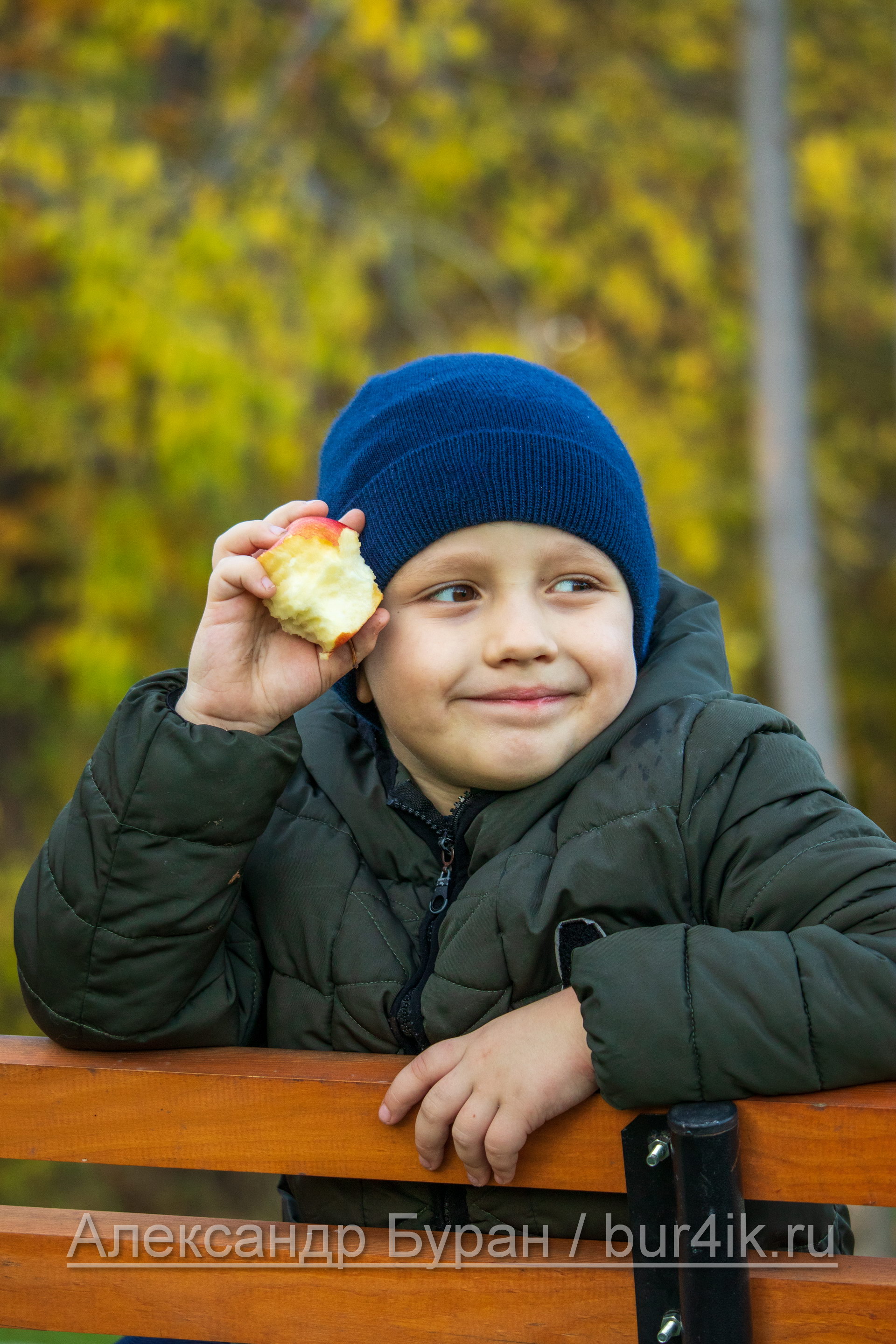 Мальчик с яблоком головы в парке осенью