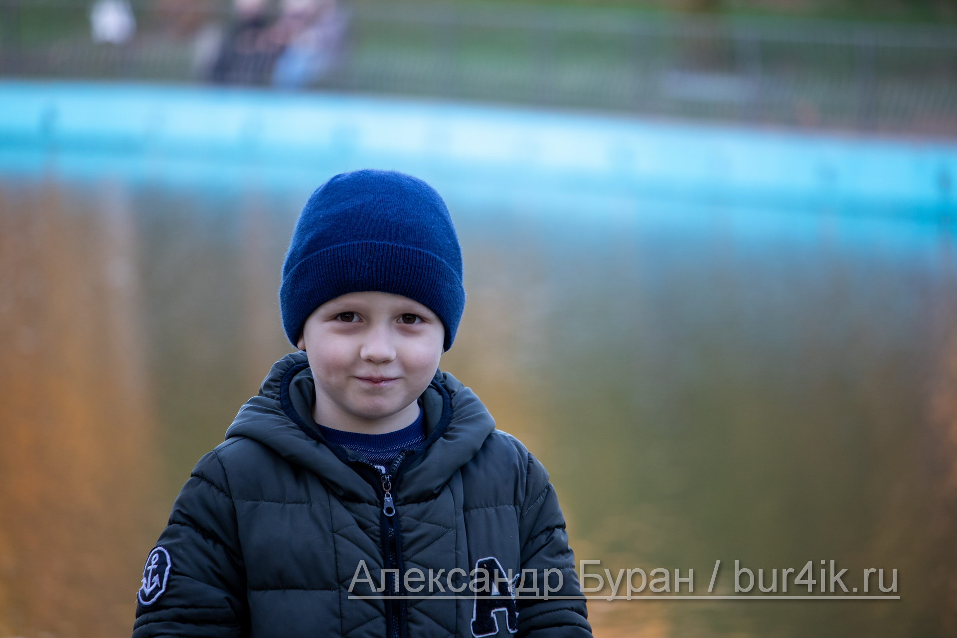 Шесть-летний мальчик осенью в парке около пруда с водой