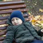 Мальчик лежит на деревянном топает осенью в парке