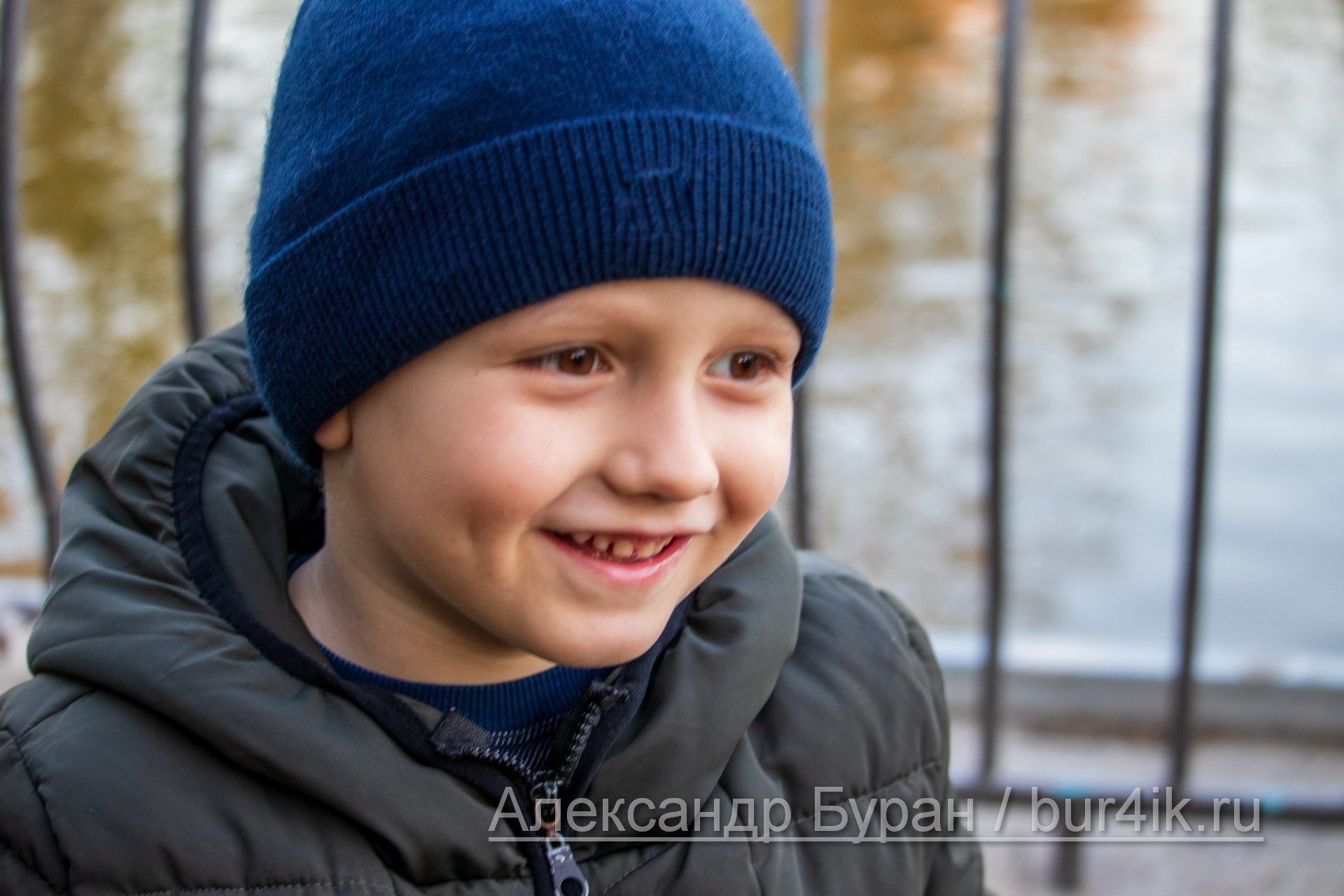 Улыбка мальчика в синей кепке на фоне озера