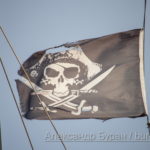 Пиратский флаг с черепом и саблями на черном фоне развивается на ветру