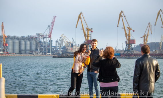 Молодая девушка и парень, которые фотографируют их родителей на прогулку в порту - Украина, Одесса, 09,11,2019