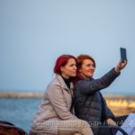 Две рыжеволосых девушки фотографируются на фоне моря в порту - Украина, Одесса, 09,11,2019