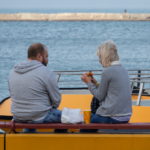 Мужчина и женщина едят бутерброд на скамейке в порту у моря - Украина, Одесса, 09,11,2019