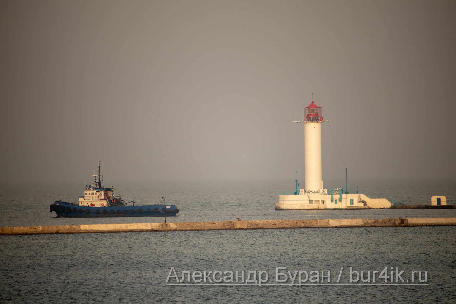 Баркас плывет в водах порта, мимо маяка на причале новый корабль - Украина, Одесса, 09,11,2019