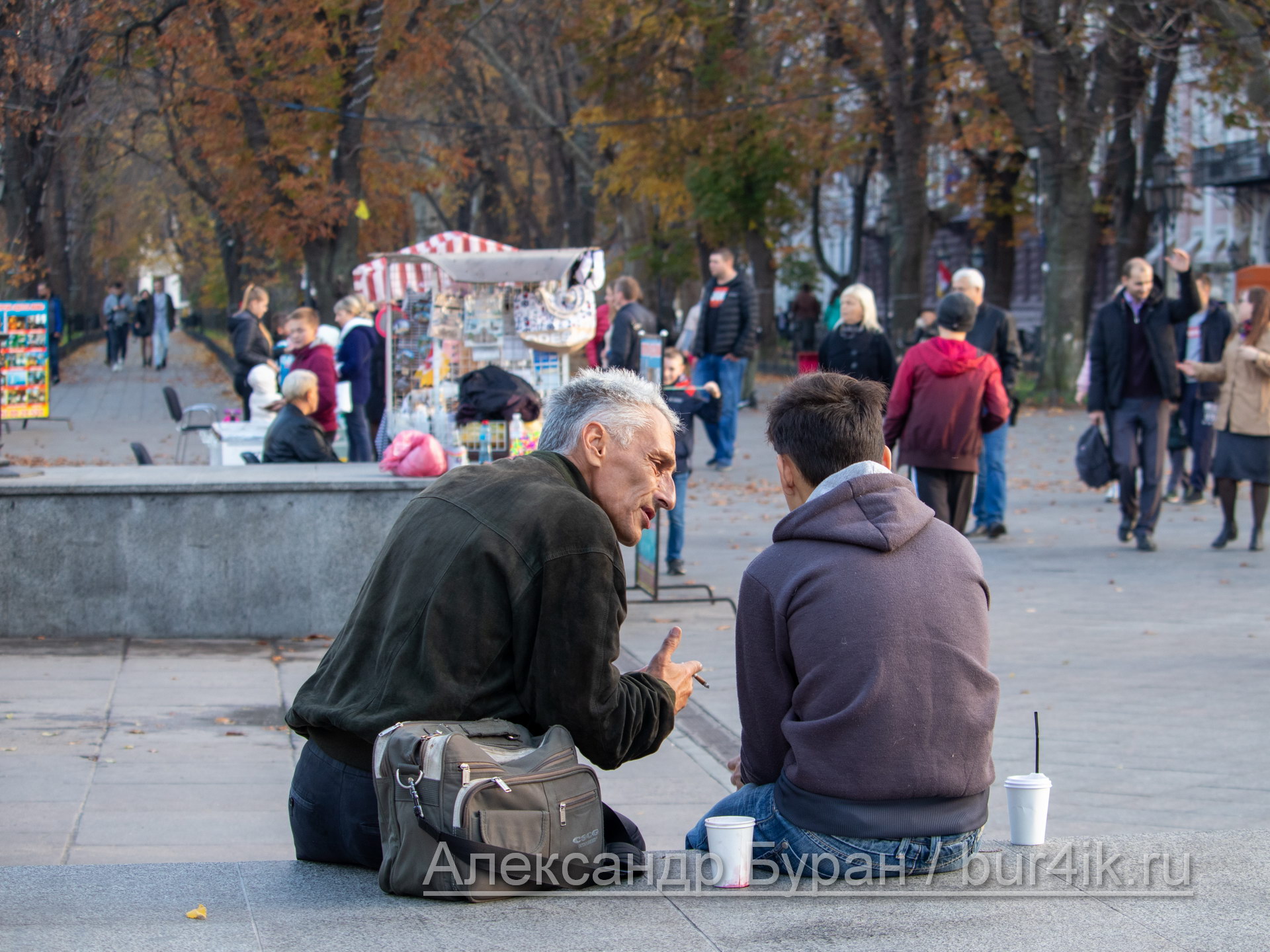 Пожилой мужчина учит жизни молодого парня, сидящего на перилах в город - Украина, Одесса, 09,11,2019