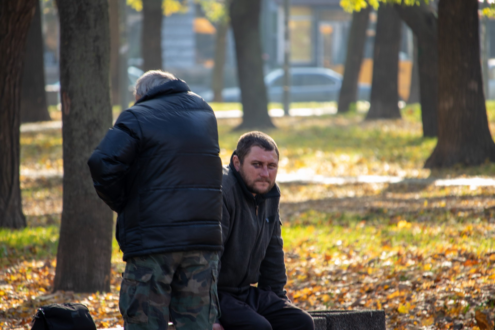 Бездомный мужчина с синяком под глазом и его товарищ на скамейке в парке осенью – bur4ik.ru фото 1