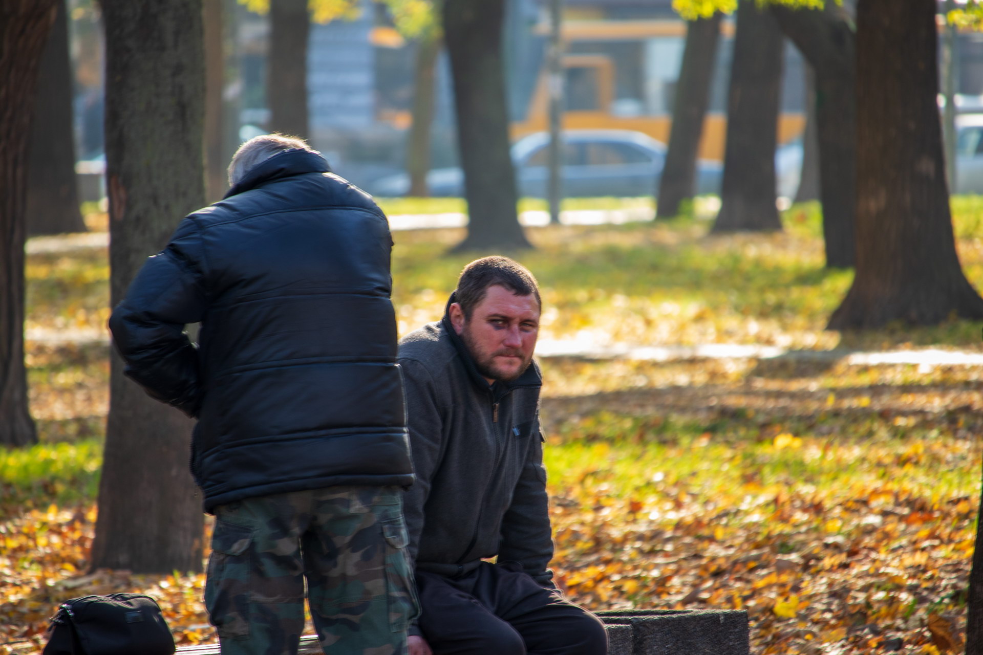 Бездомный мужчина с синяком под глазом и его товарищ на скамейке в парке осенью – bur4ik.ru фото 2