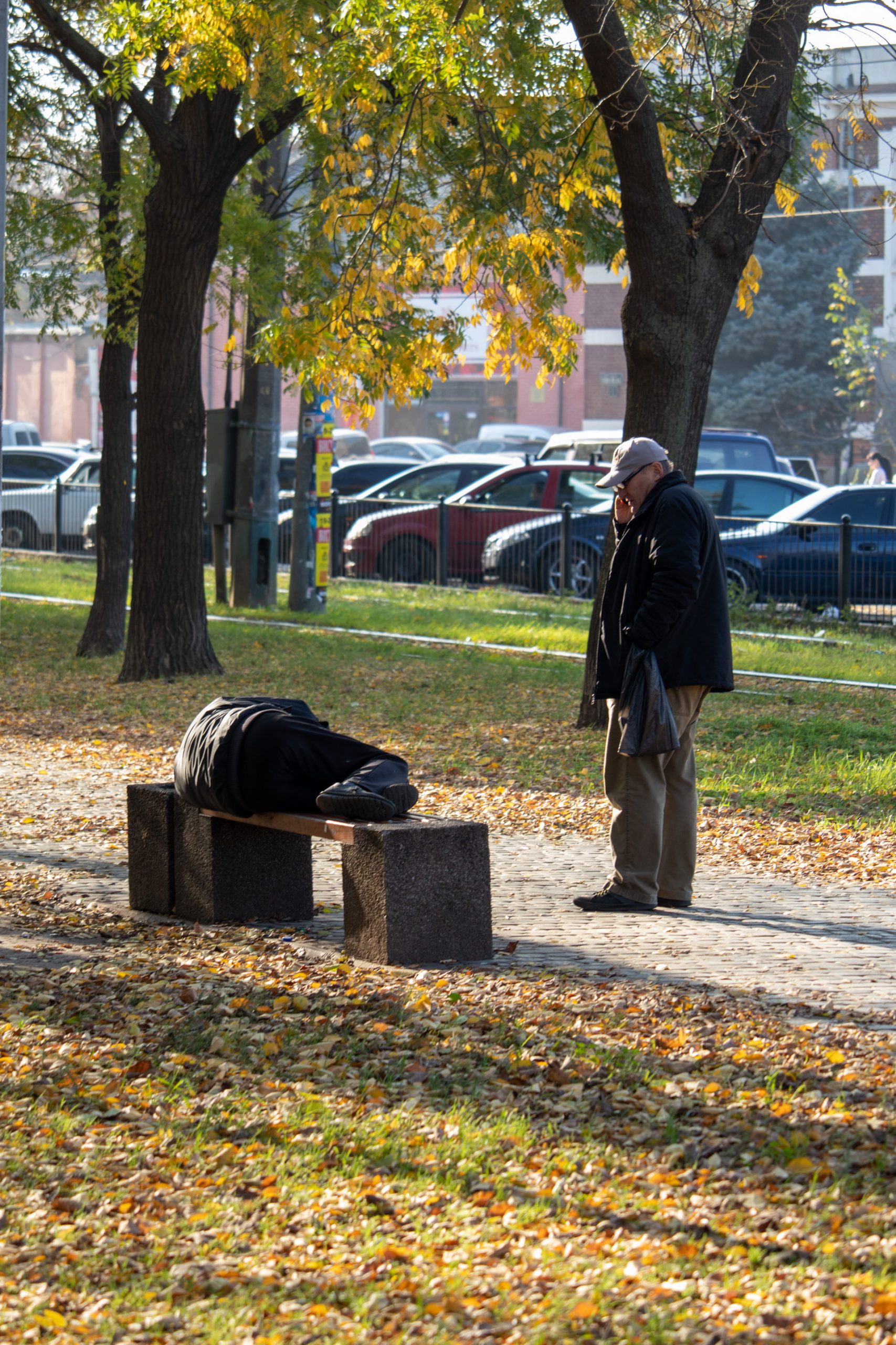Бездомный пьяный мужчина спит на скамейке прямо на улице среди прохожих осенью – bur4ik.ru фото3