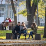 Две девушки и парень сидят на скамейке в парке осенью – bur4ik.ru фото 1
