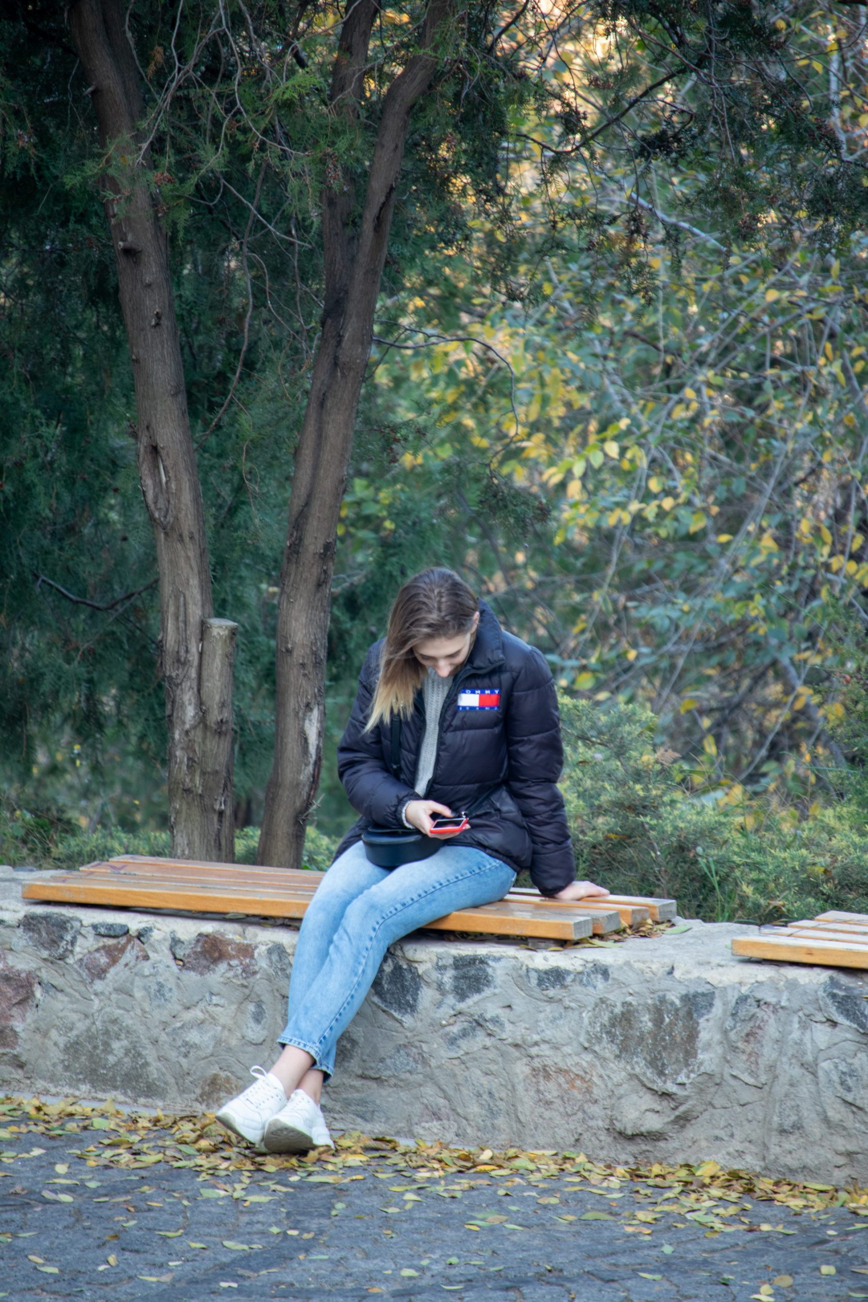 Молодая девушка сидит в парке и смотрит в смартфон – bur4ik.ru – 21.01.2020 - фото 1