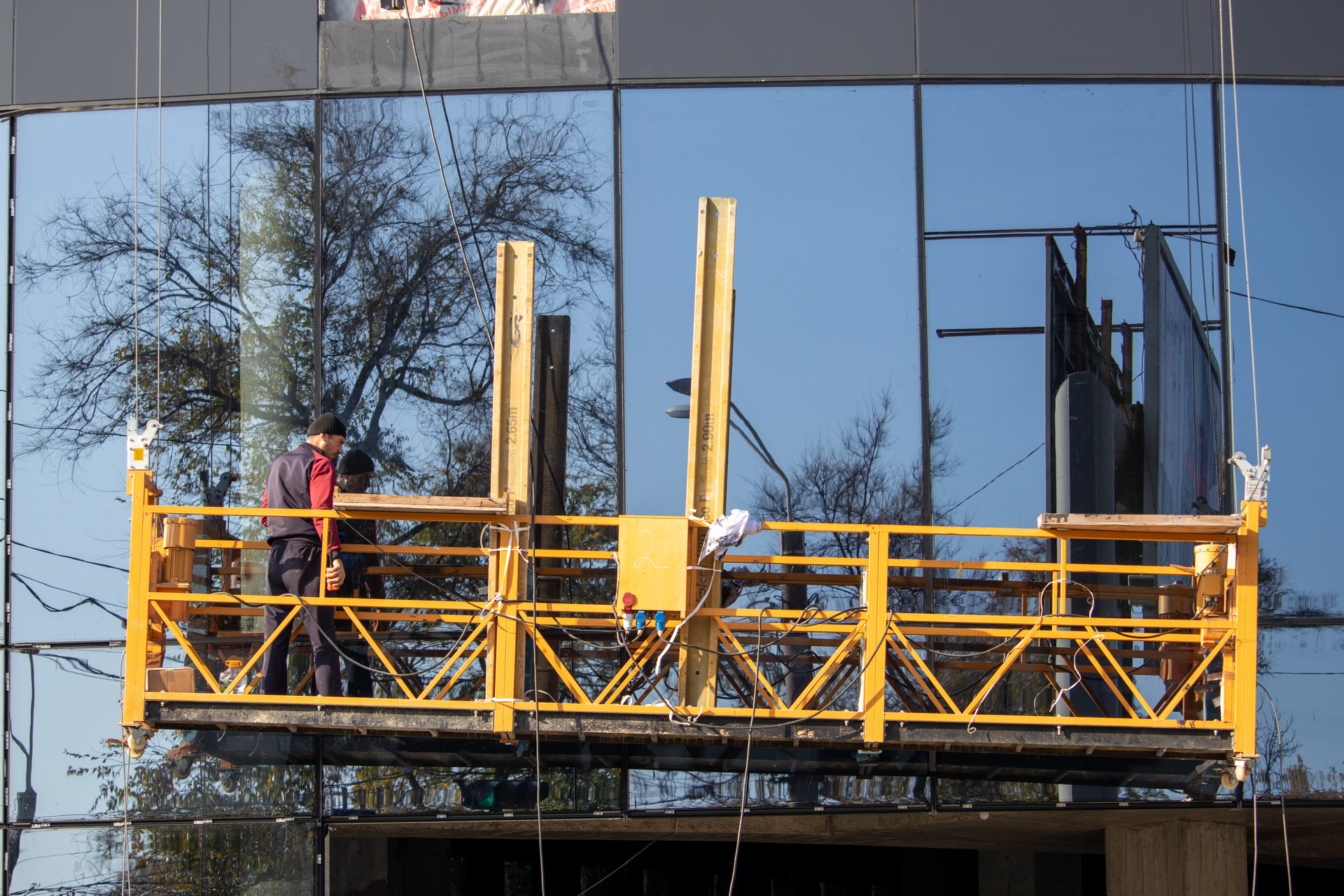 Мужчина моет стеклянный фасад здания на желтой подвесной люльке – bur4ik.ru фото 3