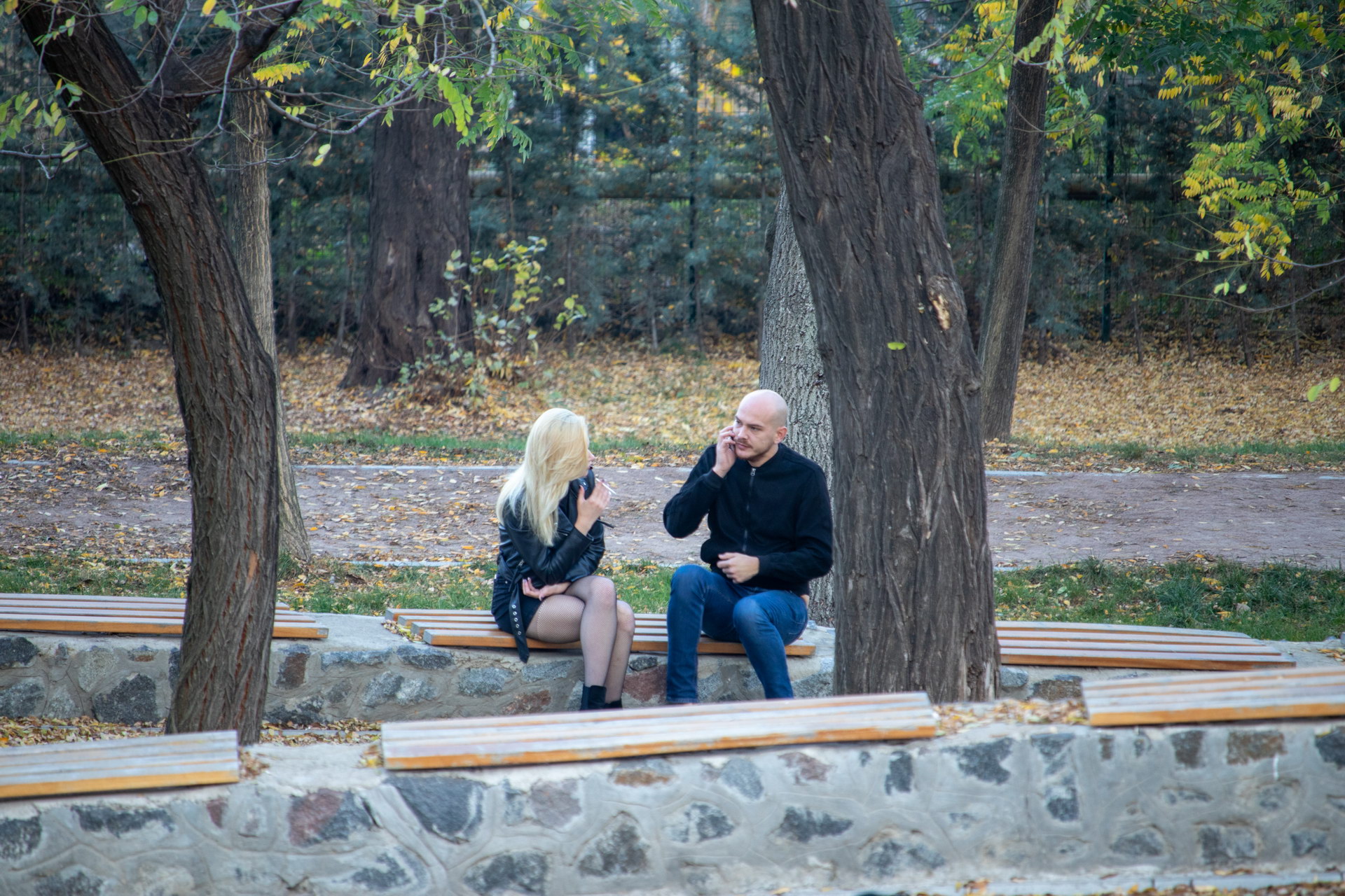 Парень на скамейке и девушка с сигаретой в руках