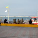 Военные сидят на скамейке у причала в порту в городе Одесса 1