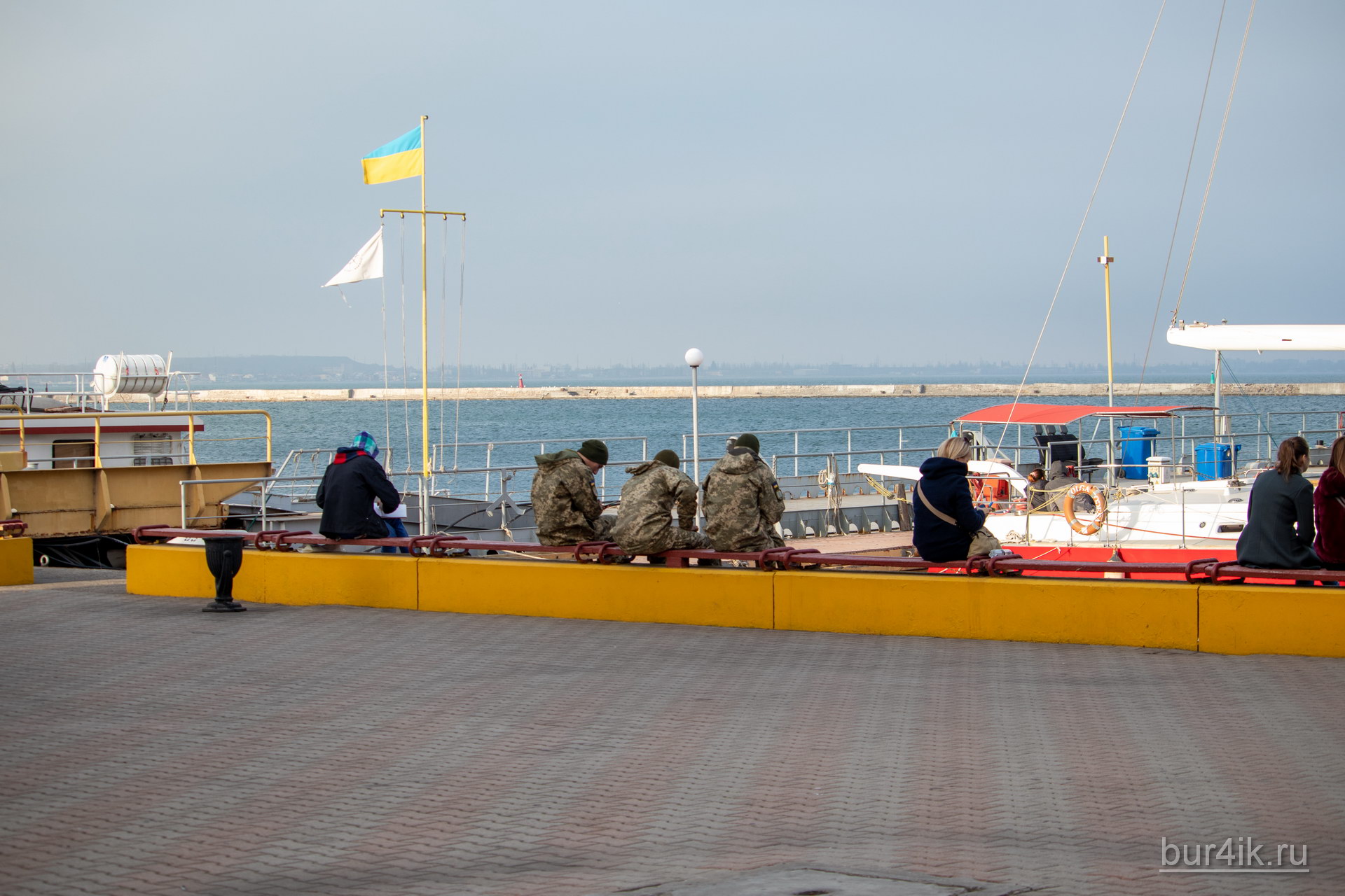 Военные сидят на скамейке у причала в порту в городе Одесса 1