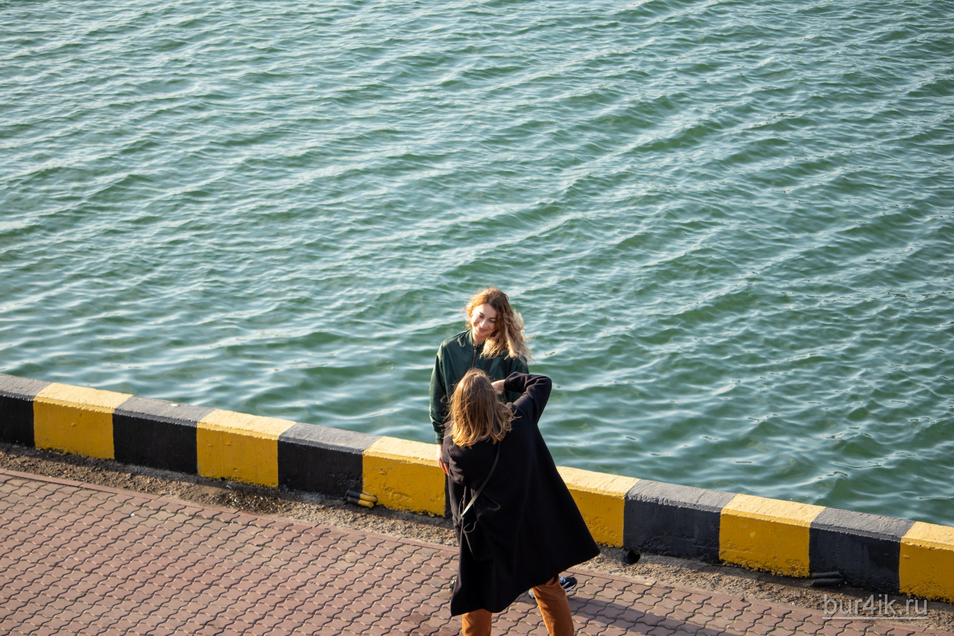 Девушка фотографирует подругу в порту города Одесса