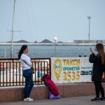 Дочка фотографирует маму на телефон в порту города Одесса