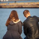 Парень и девушка сидя на скамейке делают серфи в порту города Одесса 2