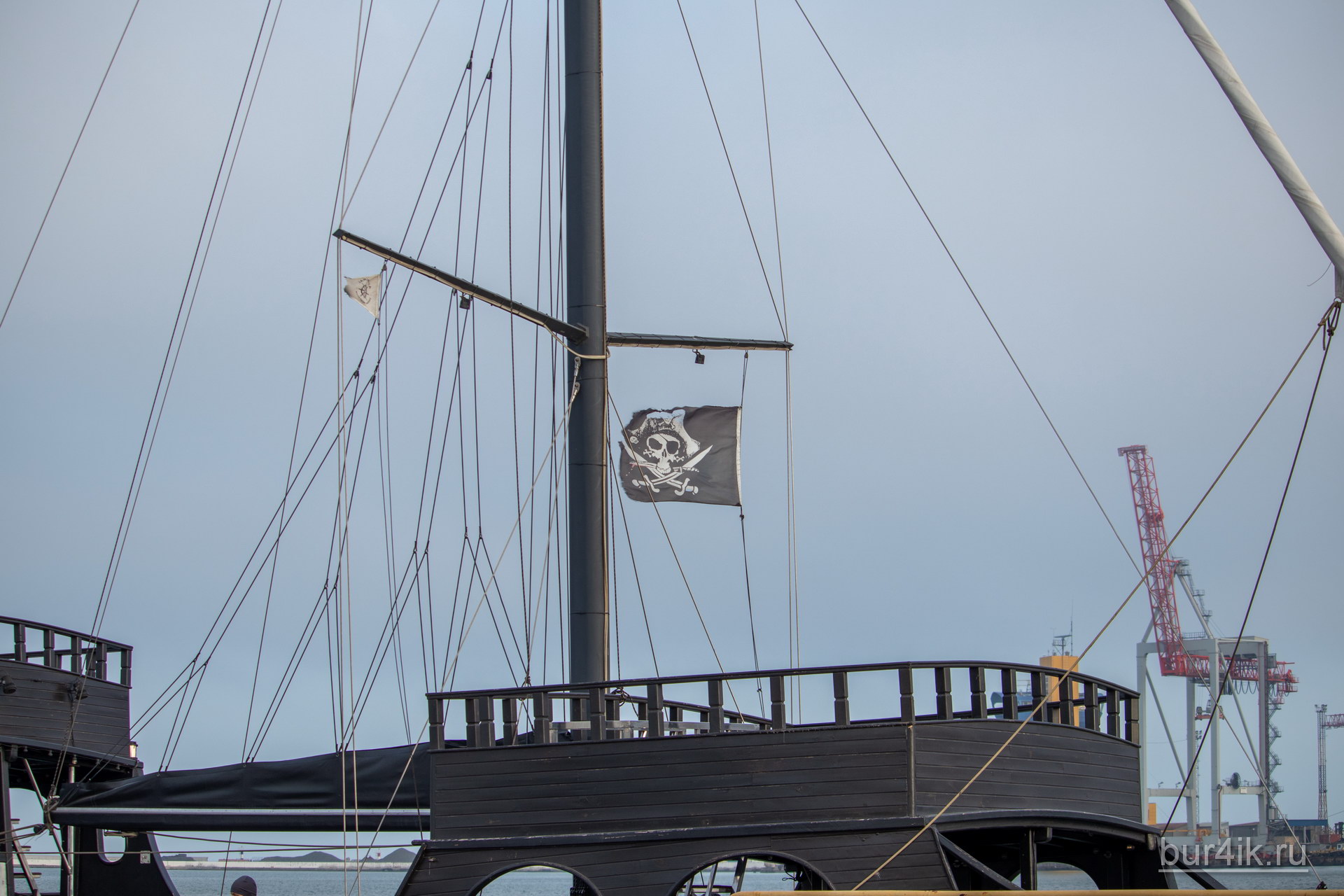 Черный пиратский флаг с черепом и саблями на мачте фрегата 1