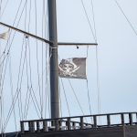Черный пиратский флаг с черепом и саблями на мачте фрегата 2