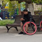 A cyclist with a phone in his hands sits on a bench - Ukraine, Odessa, 11,06,2020