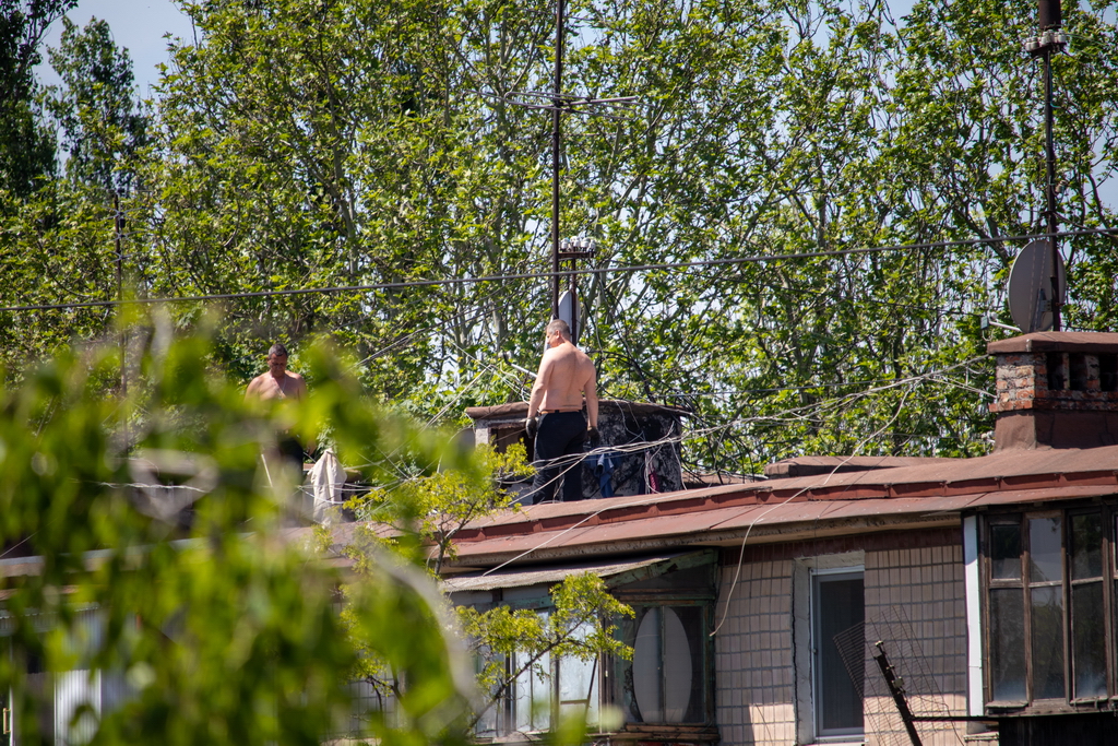 Two men fix the roof of an old house - Ukraine, Odessa, 11,06,2020