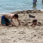 Two teenage boys on the beach digging a hole in the sand - Ukraine, Odessa, 11,06,2020