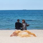 Две девушки сидят на камне у моря