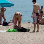 Женщина складывает вещи в сумку на пляже