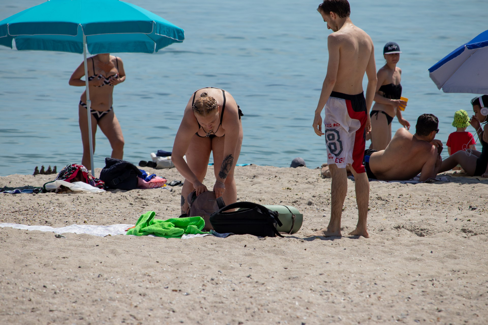 Женщина складывает вещи в сумку на пляже