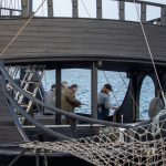 Люди ловят рыбу с палубы старинного корабля