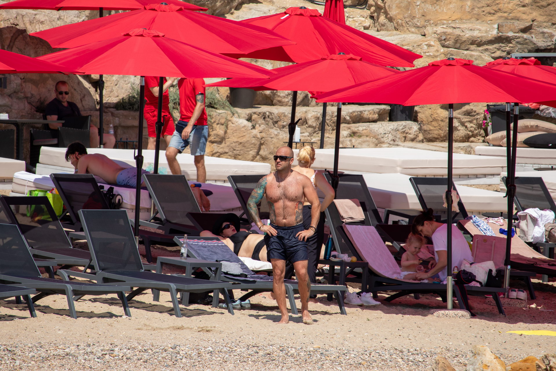 Мужчина на пляже с красными зонтами