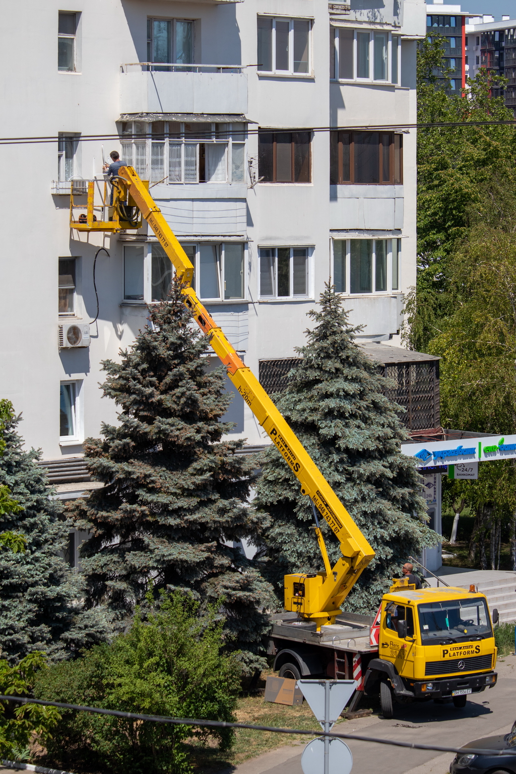 A man installs air conditioning from the cradle of a hydraulic ladder - Ukraine, Odessa, 11,06,2020
