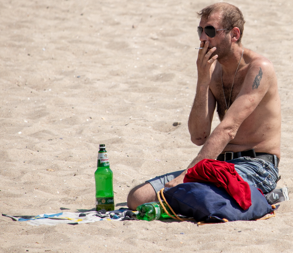 Untidy man with beer smokes on the beach - Ukraine, Odessa, 11,06,2020